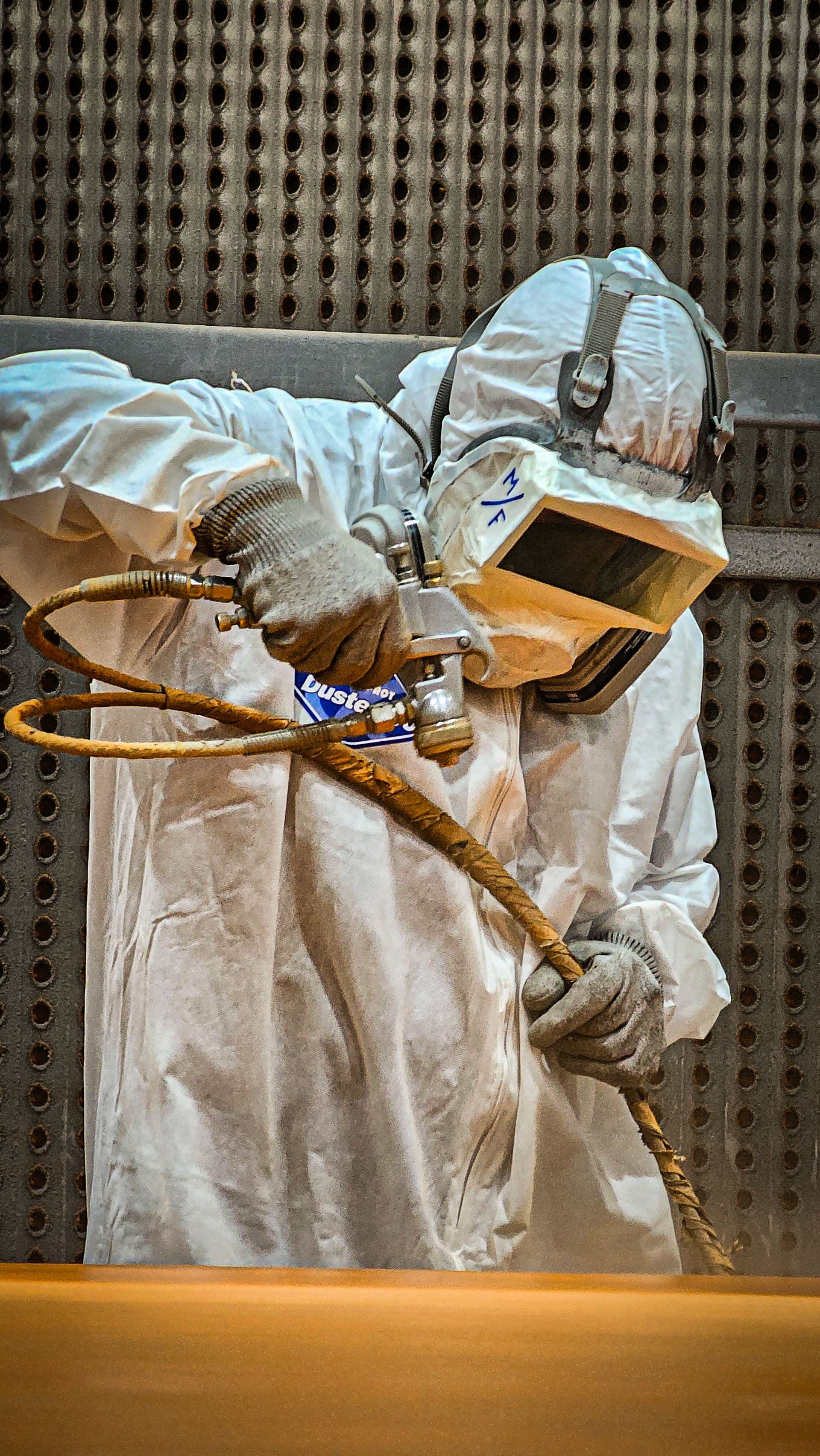 Profissional realizando pintura industrial com equipamento de proteção
