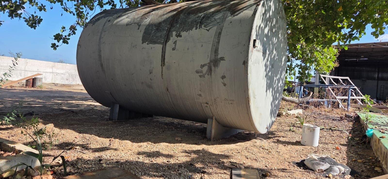 Tanque metálico horizontal com superfície escura e marcas de desgaste antes do tratamento